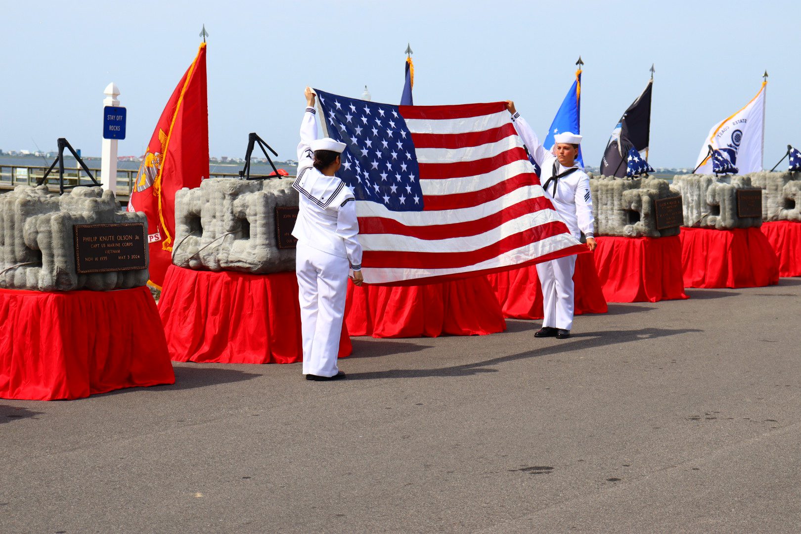Uniformed service members holding an American flag at a Veterans Memorial Reef ceremony