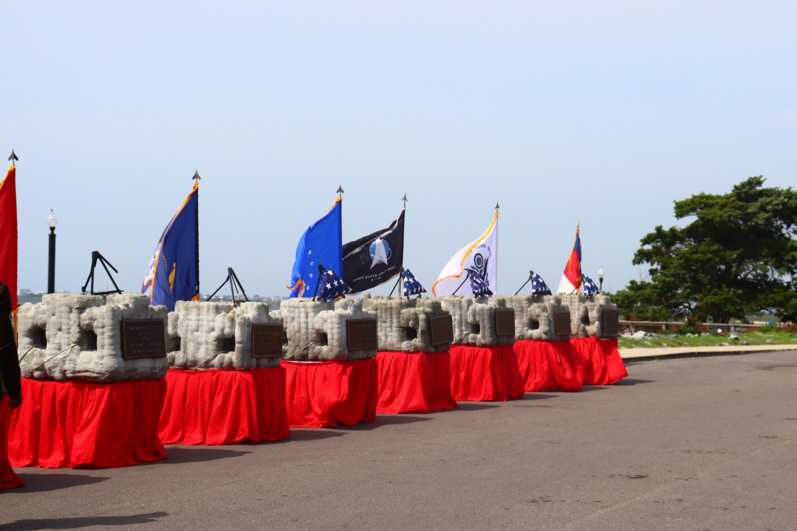 Memorial markers displayed with American and military service flags before a ceremony